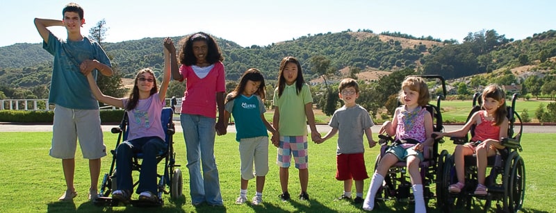 magical bridge marin accessible inclusive playground project info Boys and girls in all ages with disabilities standing together holding hands